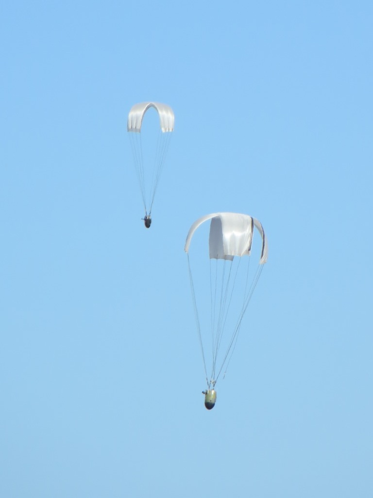 Figure B. Double airdrop of cross-type parachute systems (a), and two systems rigged for deployment (b).