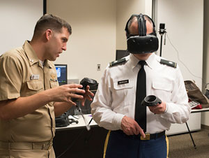 NPS alumnus Lt. Clay Greunke, left, explains a virtual reality simulation to Modeling, Virtual Environments and Simulation (MOVES) Institute Deputy Director Army Lt. Col. John Morgan, right, at the MOVES Institute Academic Working Group in Watkins Hall, May 24.