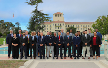 a picture of participants in formal attire standing along side with each other in front of a sky blue pool