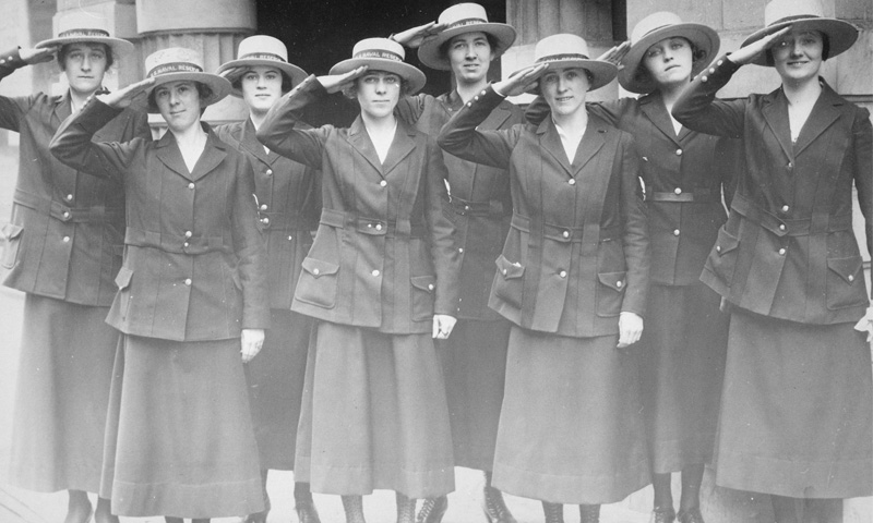 Eight female yeomen attached to the Naval Reserve stand together in uniform saluting, San Francisco, California, June, 1918. 