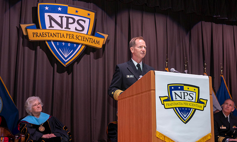 NPS graduate Vice Adm. John Mustin, Chief of Navy Reserve on stage at the 2023 Winter Graduation commencement ceremony.