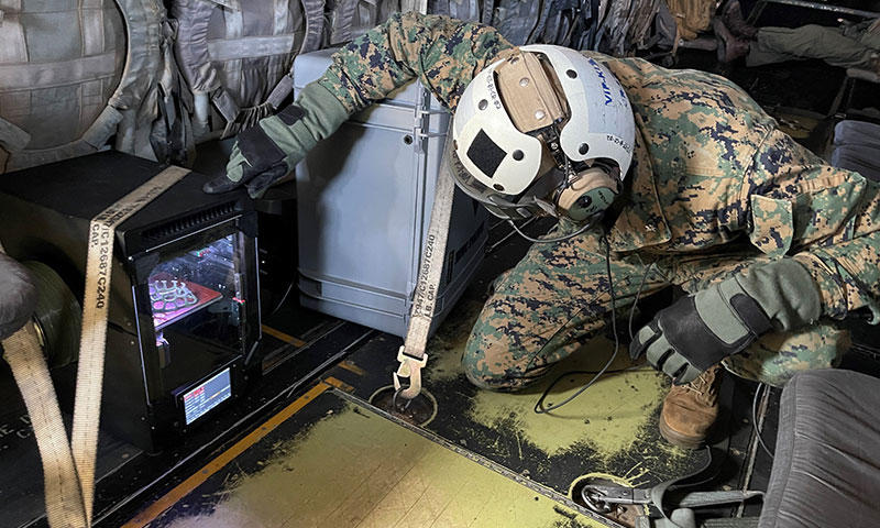 U.S. Marine Corps Lt. Col. Michael Radigan checks on the 3D printing aboard an MV-22 Osprey 