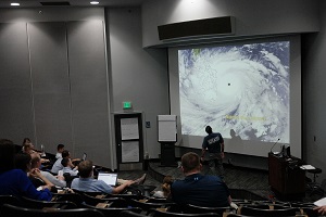 Participants watching projector screen with hurricane image on it