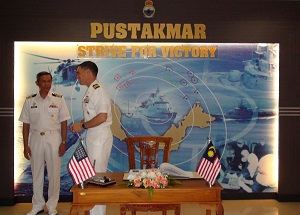 Two officers in white uniforms in front of a collage image of naval ships