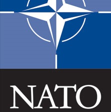 White graphical compass over blue with a black bar on the bottom containing the word NATO