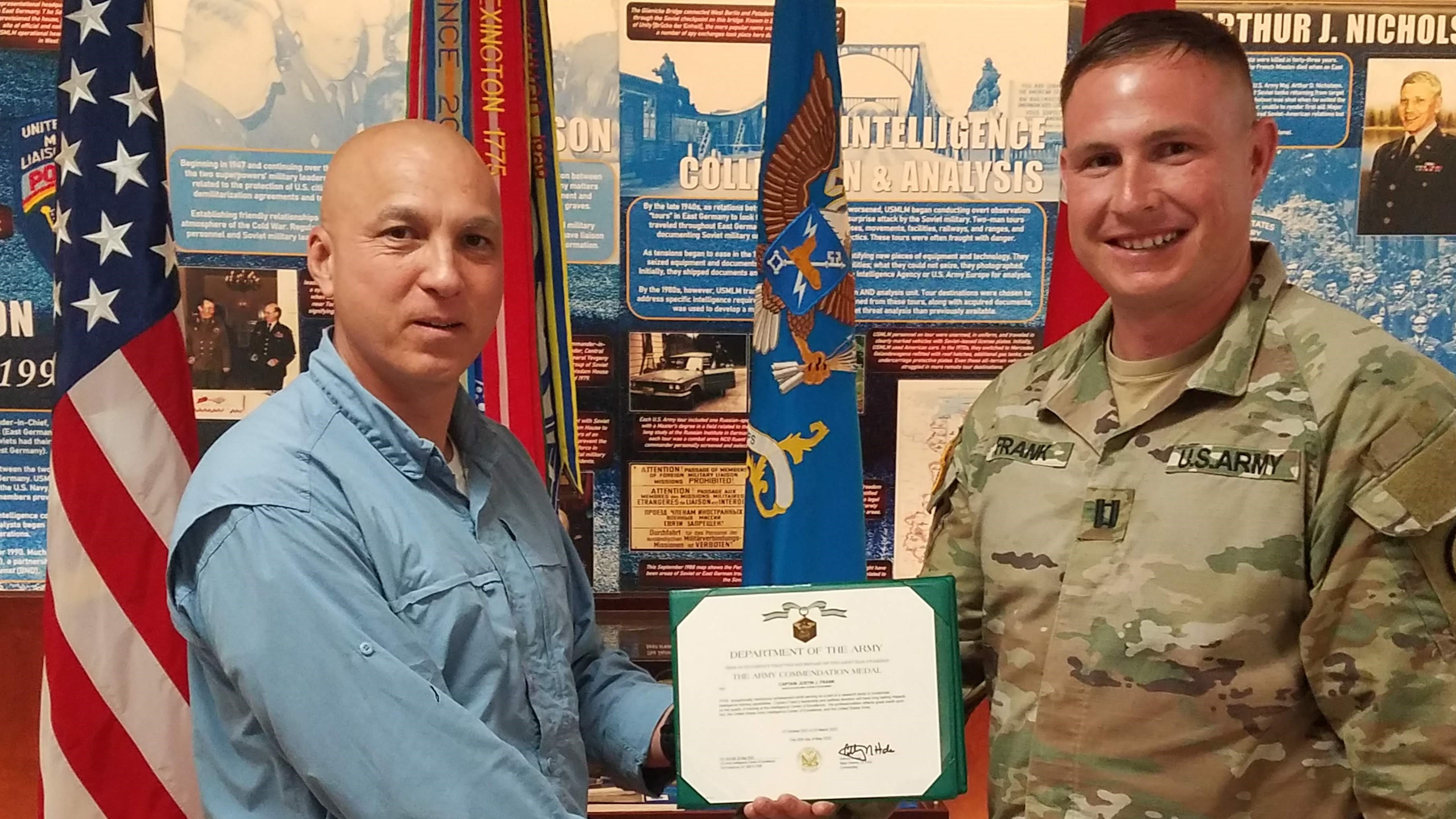 CPT Justin Frank receives an Army Commendation Medal from Mr. Pete Don, SES, USAICoE, Fort Huachuca for his thesis using VR to train intel analysts.